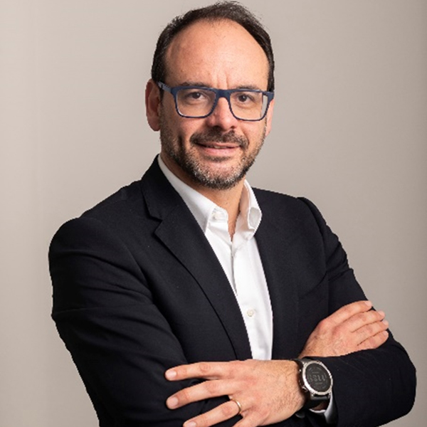 Paolo Raia in giacca nera posa con le braccia conserte, indossando un orologio argentato su uno sfondo neutro.