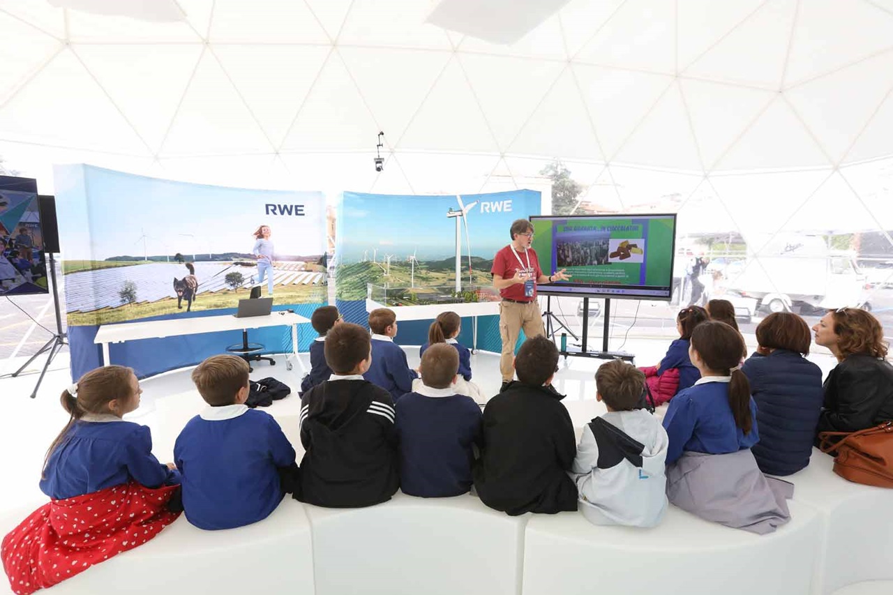 Un presentatore coinvolge i bambini in un ambiente a cupola con esposizioni educative sulle energie rinnovabili.