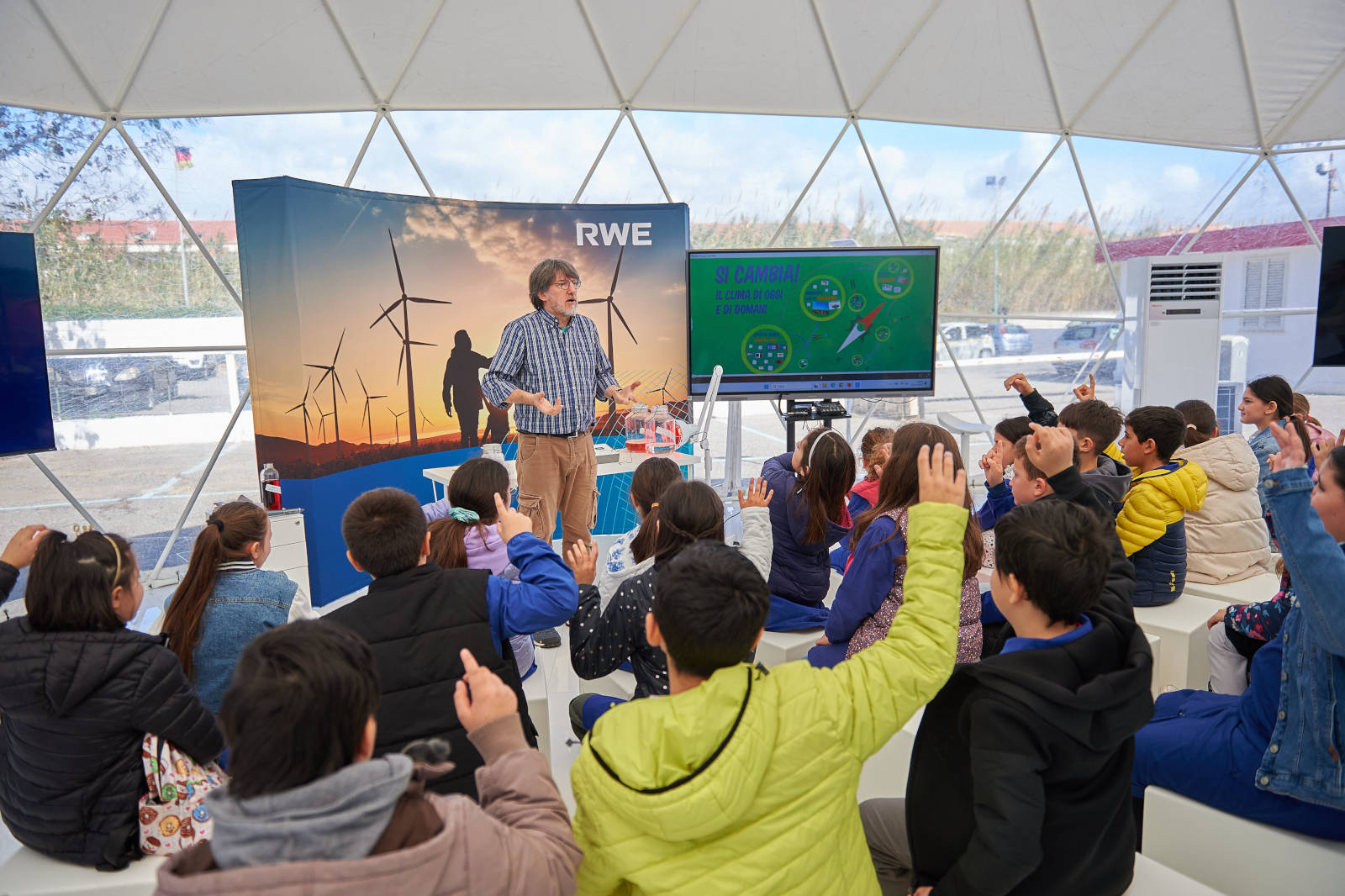 Un presentatore coinvolge i bambini durante una sessione educativa sull'energia eolica in una cupola geodetica.